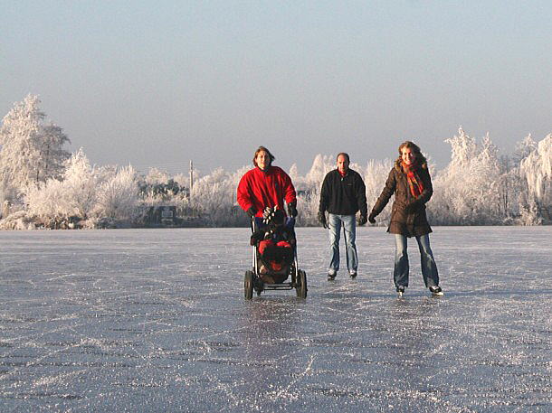 Ice-skating family with a baby in buggy